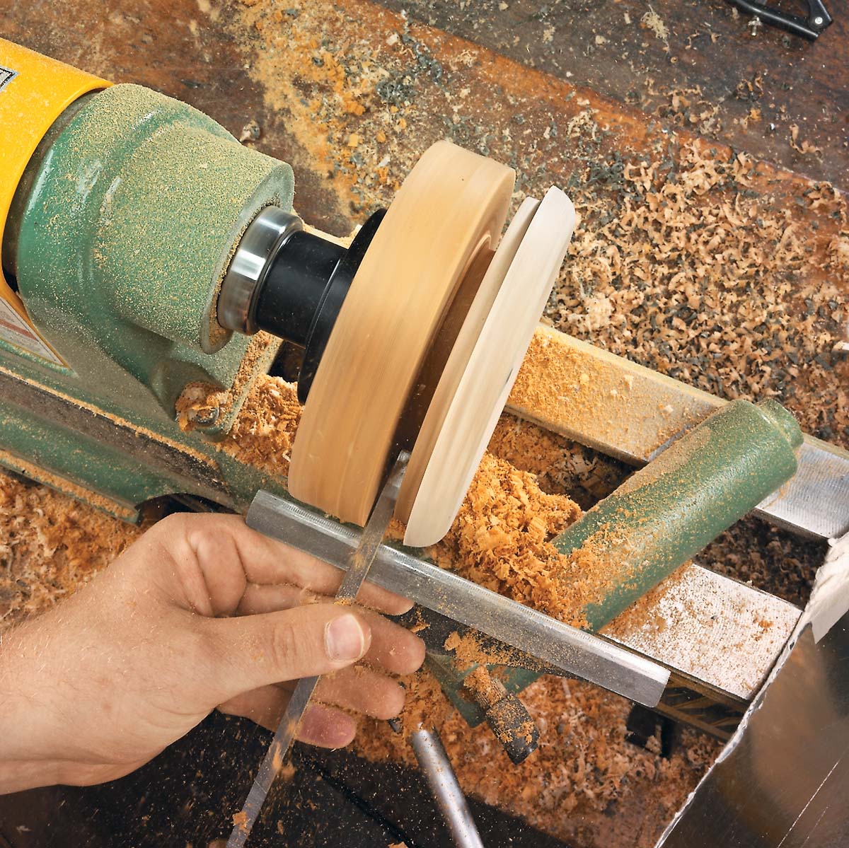 Using a parting tool to cut down the glue block side of the joint line to seperate the lid