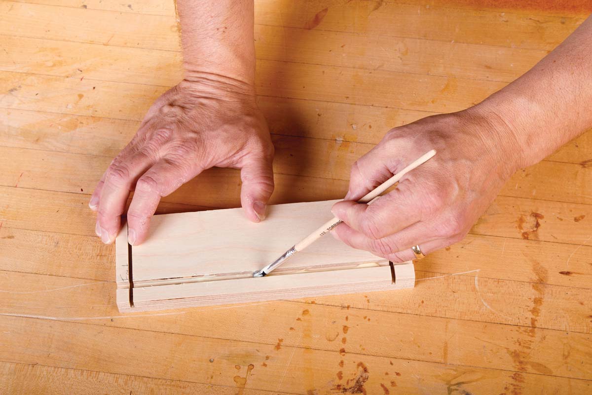 small round glue brush spreading glue in thin groove in wood