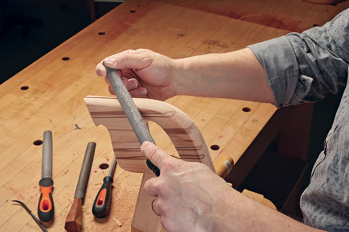 fine rasp being used on wooden saw handle