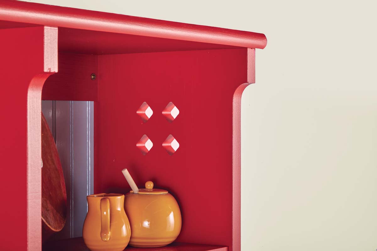 wooden wall shelf painted red with thin coats, with cut out diamond pattern on the side
