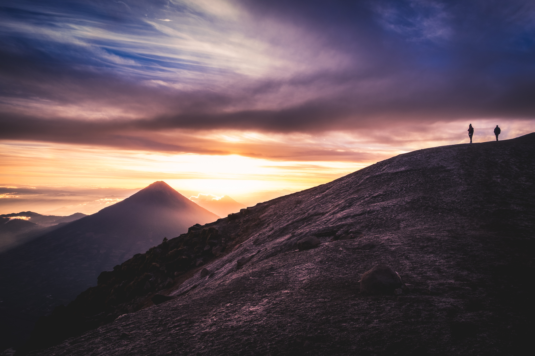 Hikers on a volcanic ridge at sunset