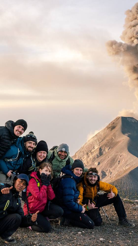 Hikers on Acatenango with Fuego erupting behind them, Guatemala
