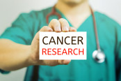 Doctor holding a business card with capital lettering cancer research