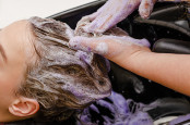 Hairdresser applying dye purple shampoo after hair dye