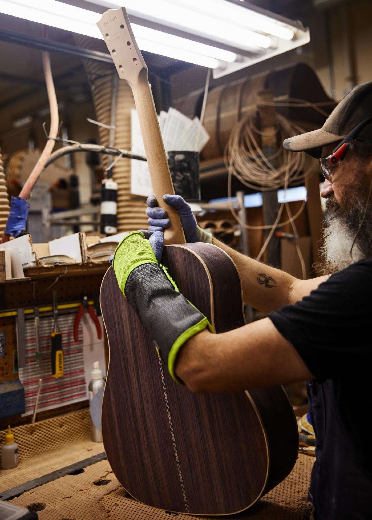 An artisan fits a J-45 Deluxe Rosewood neck.