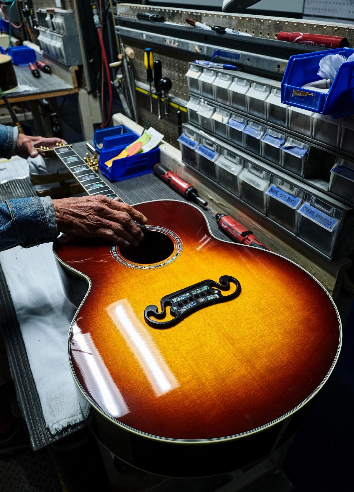 A Gibson SJ-200 in Rosewood Burst makes its way through final set up.
