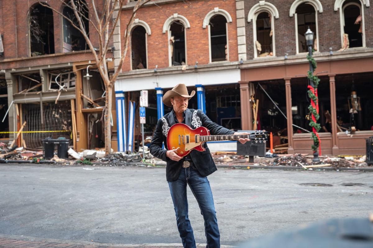 Musician Buck McCoy poses with his new Gibson Les Paul from the Gibson Gives’ Play It Forward program in front of his apartment which was affected by the recent Nashville bombing.