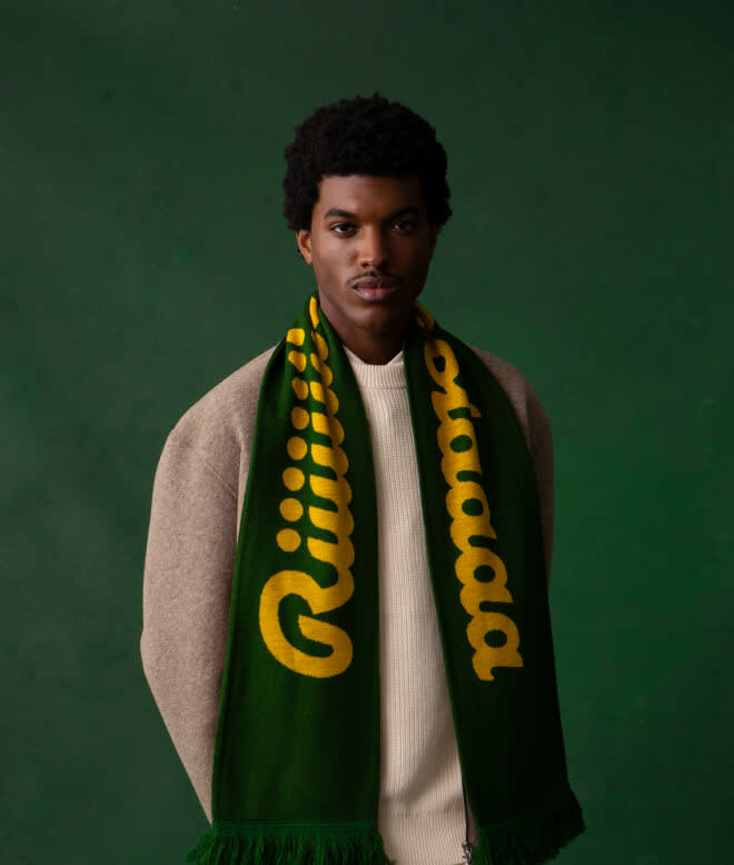Man wearing the Ricola scarf over a beige sweater