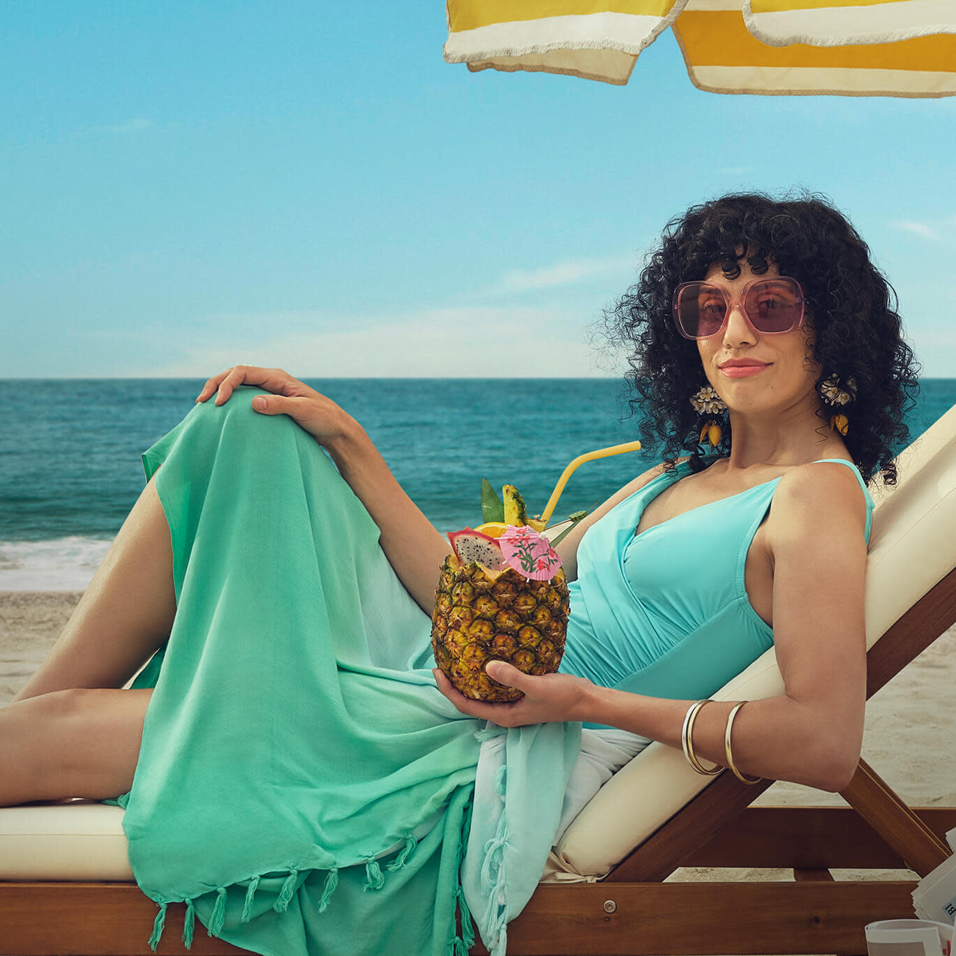 Woman drinking out of a pineapple on a beach chair 