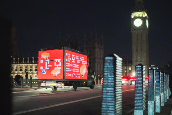 A box truck adorned with unintelligible alien ads drives near Big Ben  