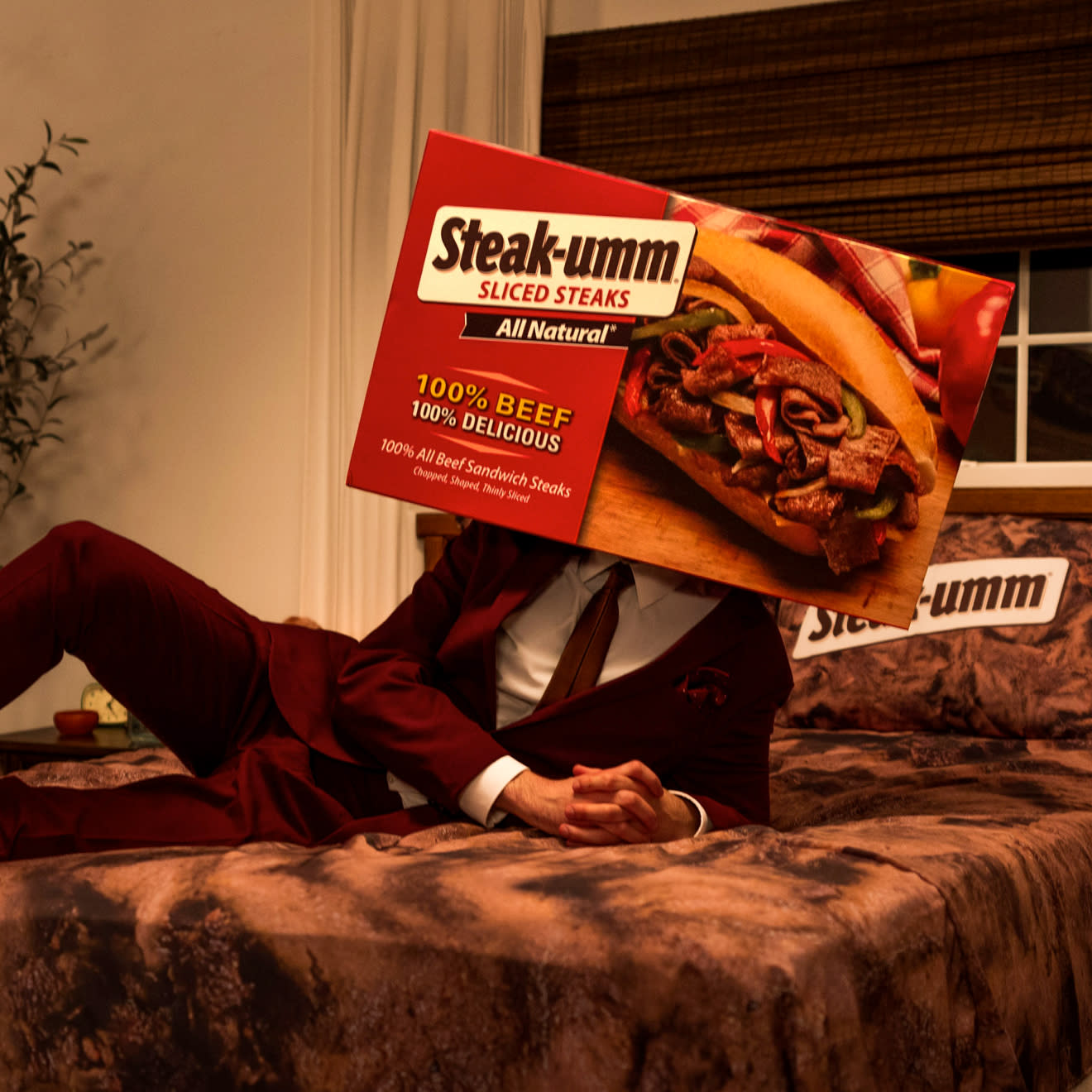 Steak-Umm Beef Sheets promo of a man lying on a bed covered in Beef Sheets sheets