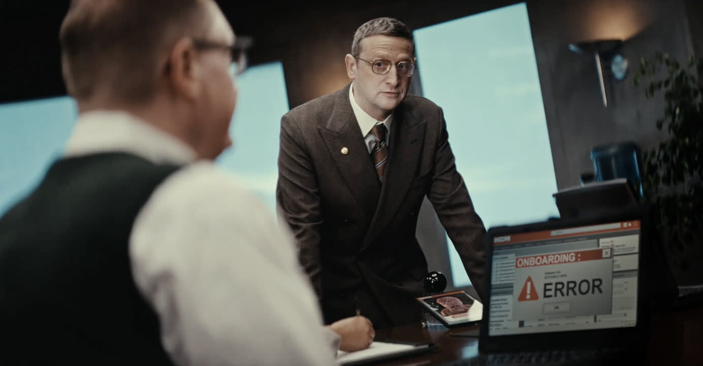 Tim Robinson glaring with intense irritability at a man whose computer shows an HR onboarding error