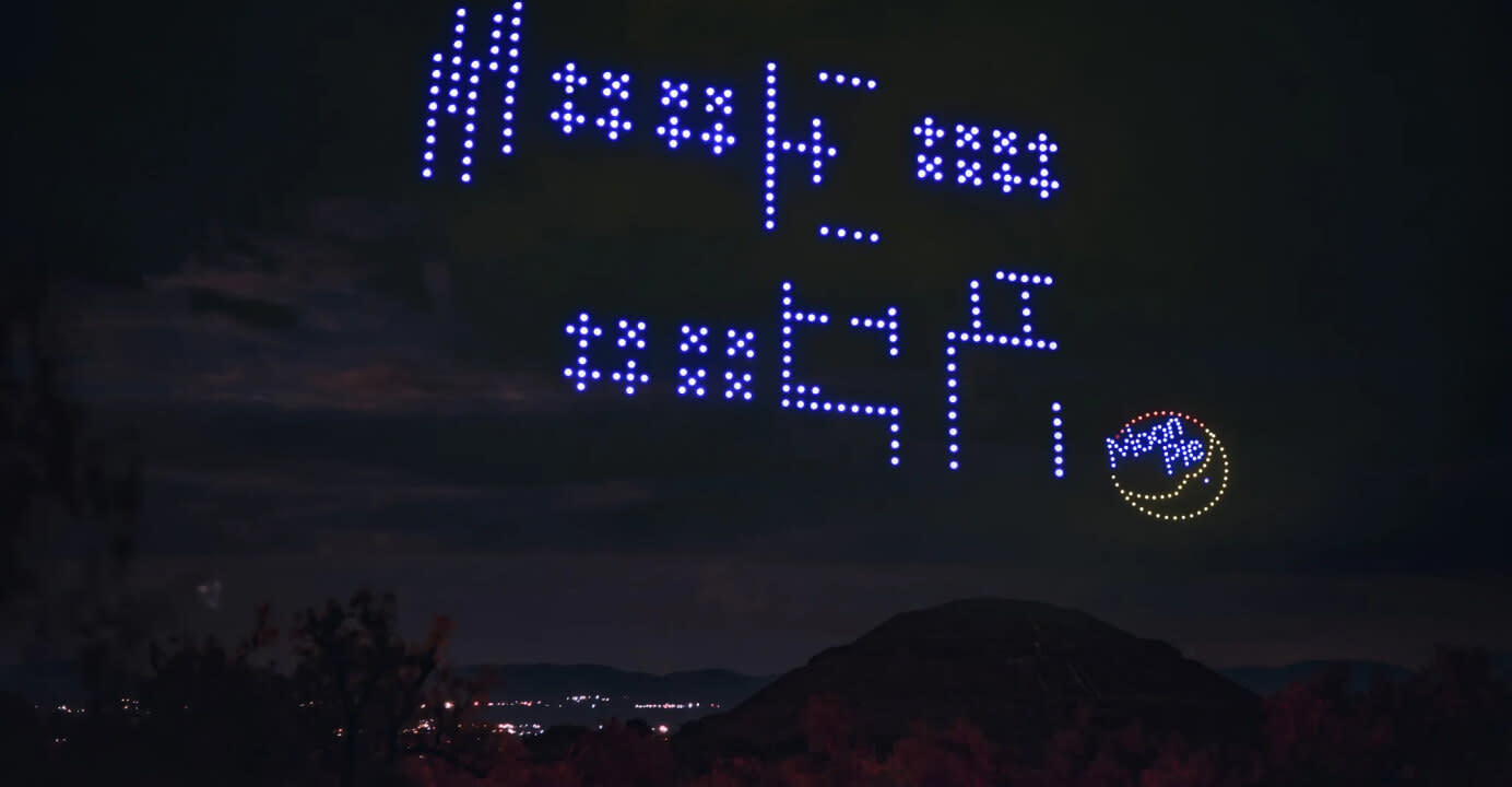 Many drones lighting up the sky in an alien language alongside a MoonPie logo