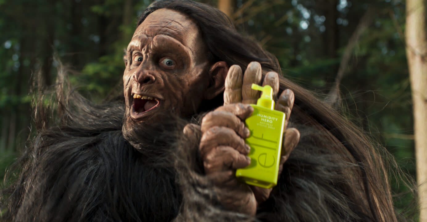 A smiling, friendly Bigfoot holding e.l.f. Humidity Hero