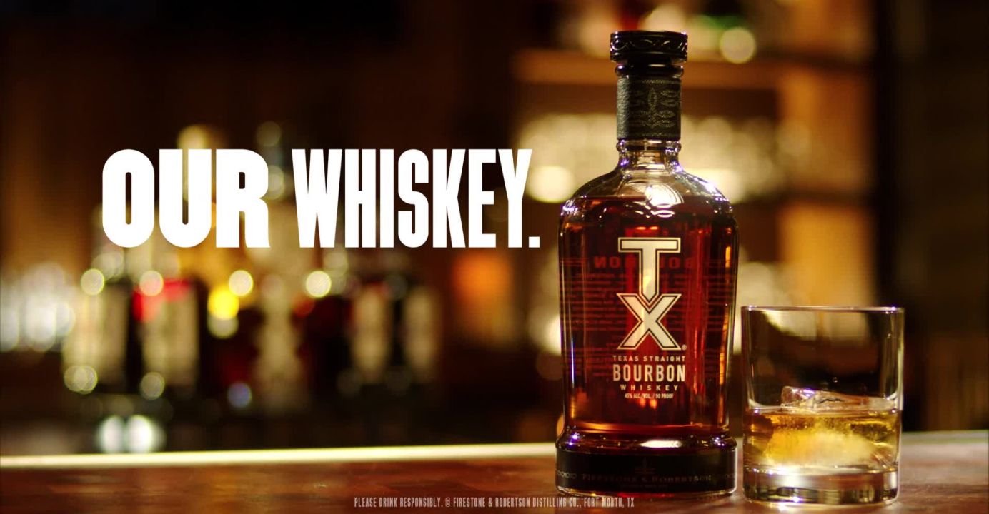 TX Whiskey "Our Whiskey. Our Way" campaign still, bottle of TX Whiskey next to a glass, 'Our Whiskey'