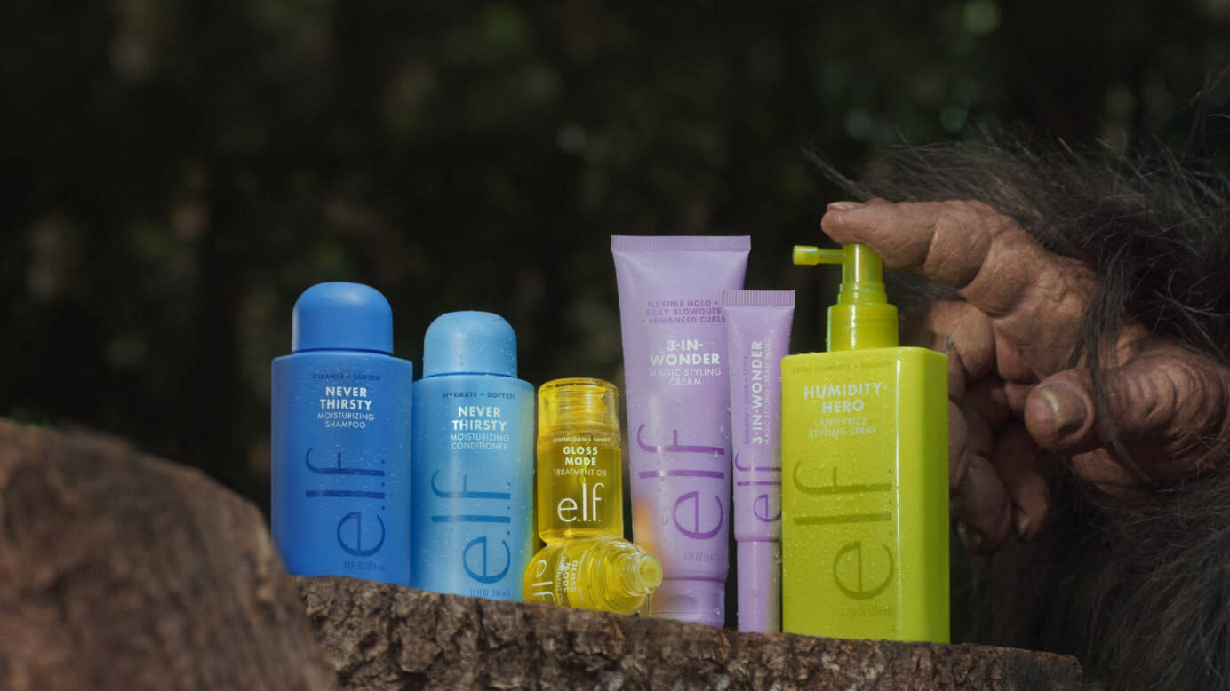 New e.l.f. hair products sitting on a log with the finger of Bigfoot touching the handle of one