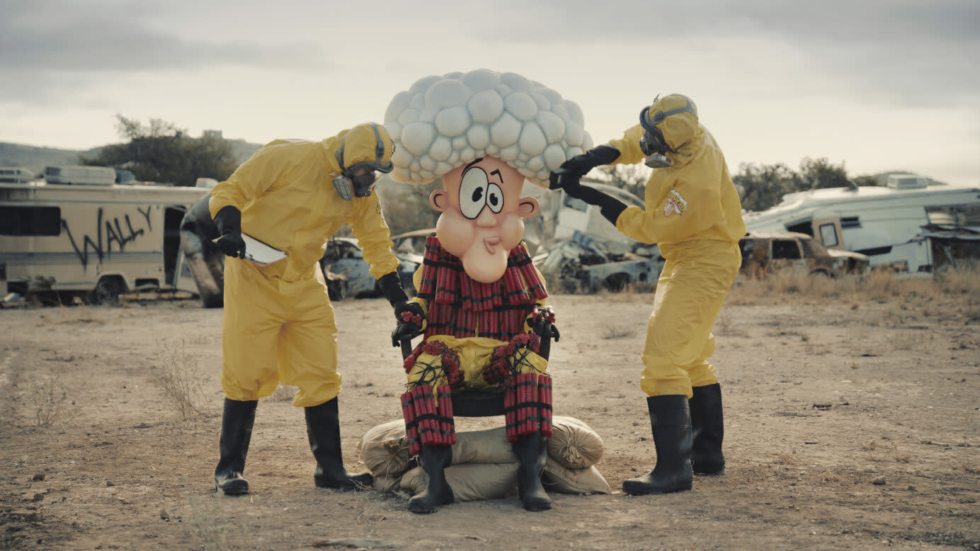 2 scientists in hazmat suits strapping Wally into a chair