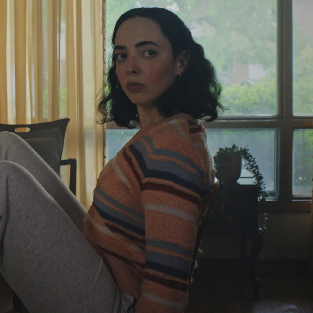 Woman in a sweater looking confused at the camera 