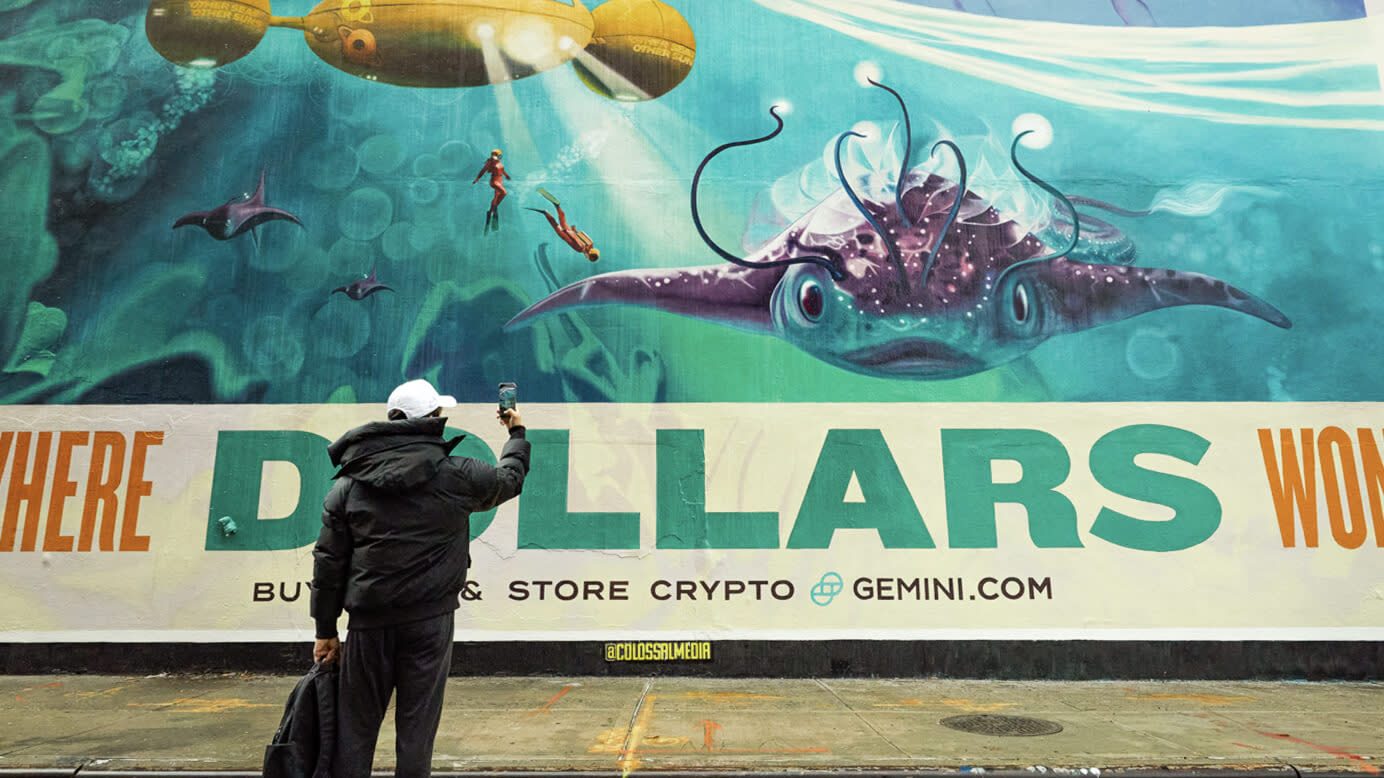 A man on a sidewalk takes a photo of the aquatic creature on a Gemini billboard