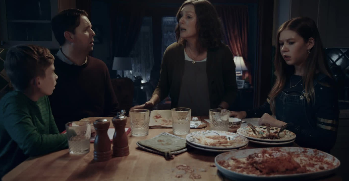 A family of four sitting at a dining table with leftovers 