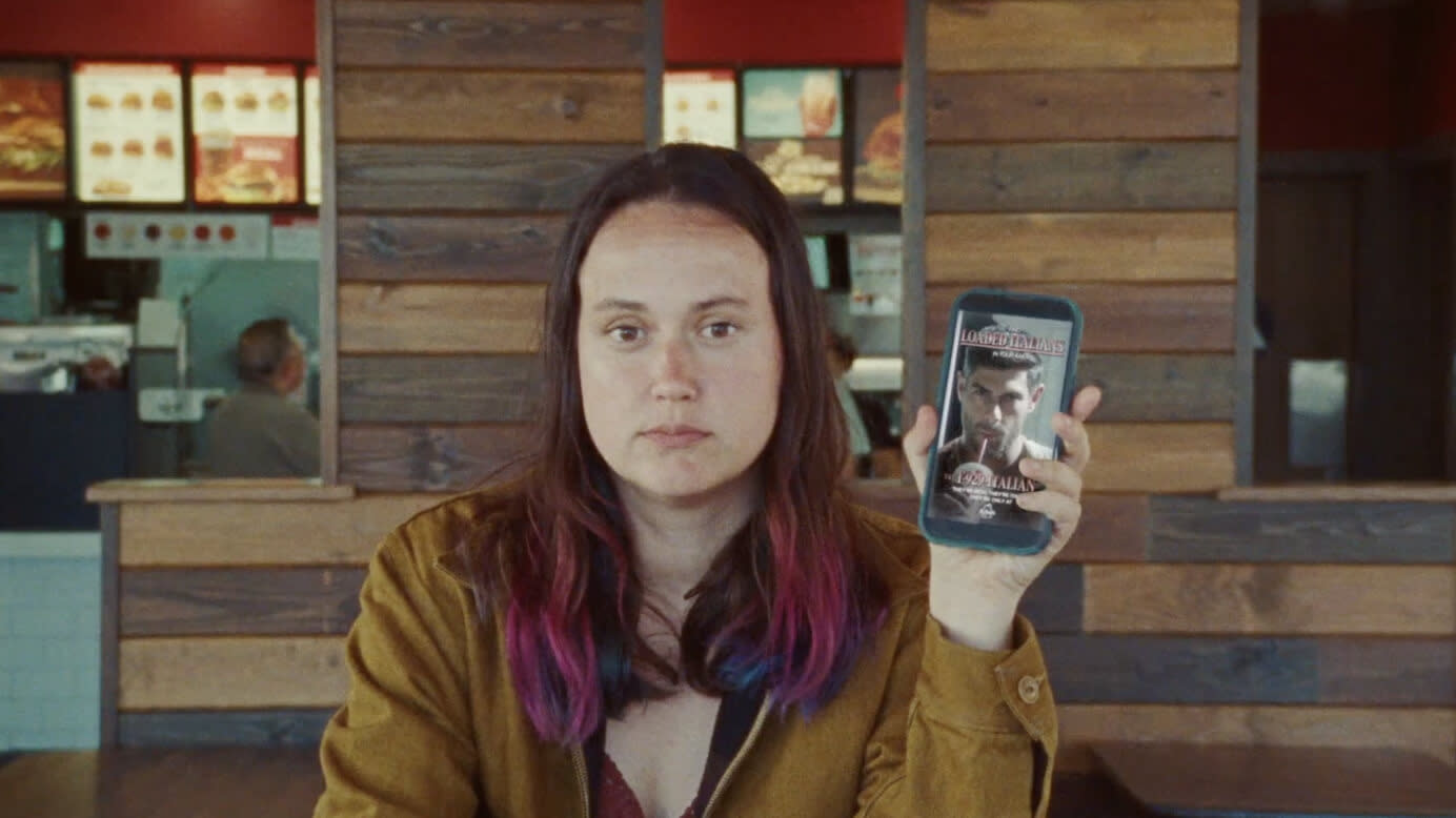 Cathy, a woman, holding her phone with hot Italians in an Arby's serving Hot Italians