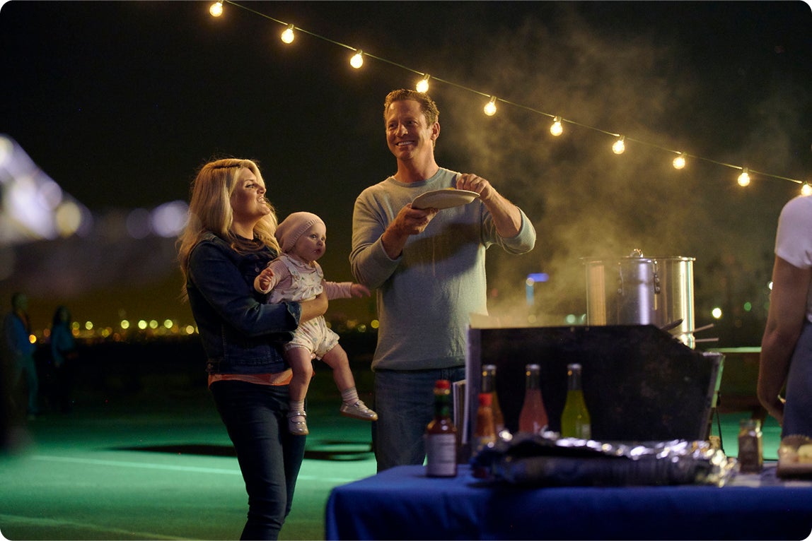 A smiling family enjoying food together at an outdoor night market, highlighting confidence and comfort eating after dental implant treatment.
