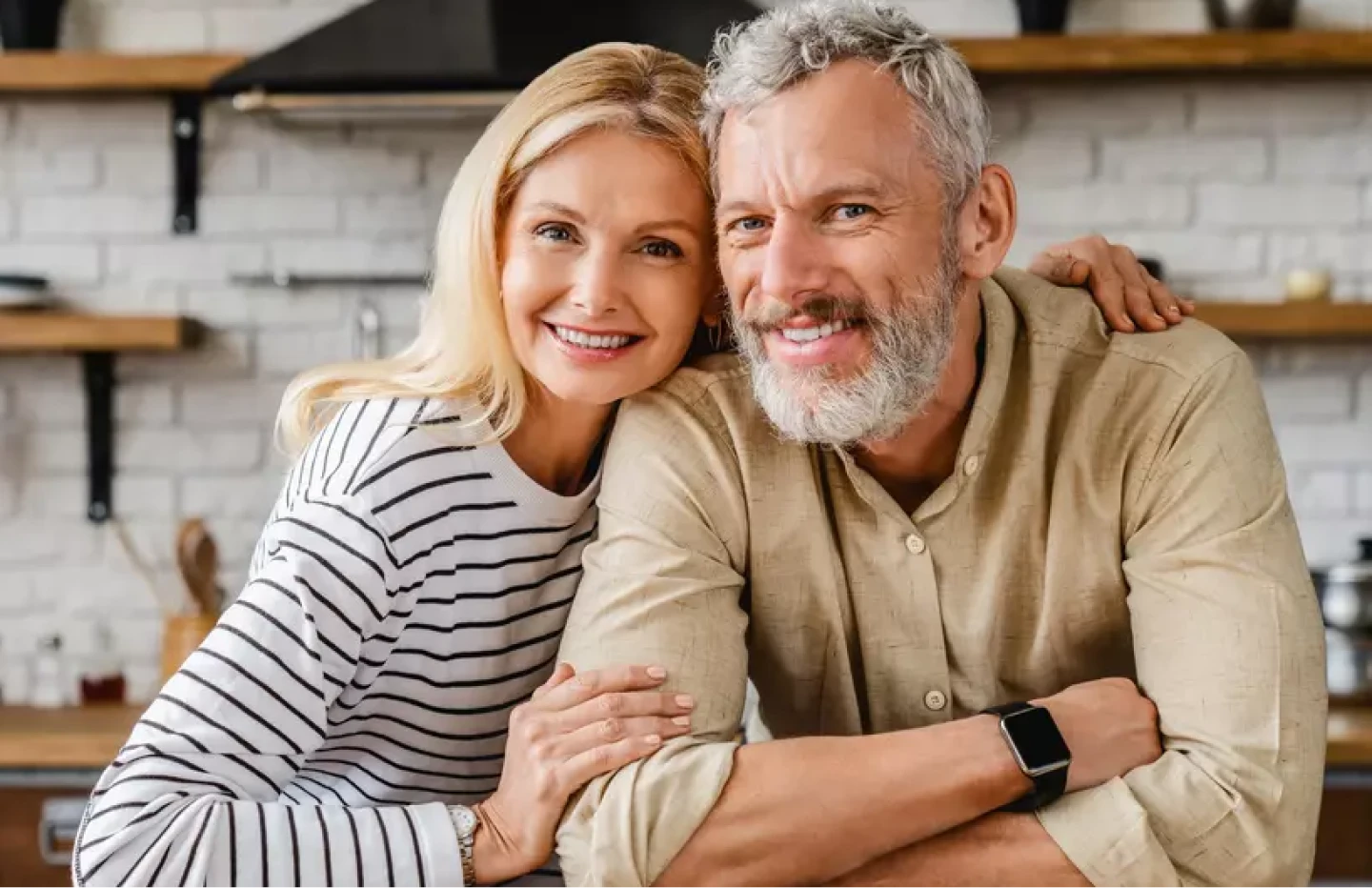 An Implant Dentures couple smile together in the kitchen. 