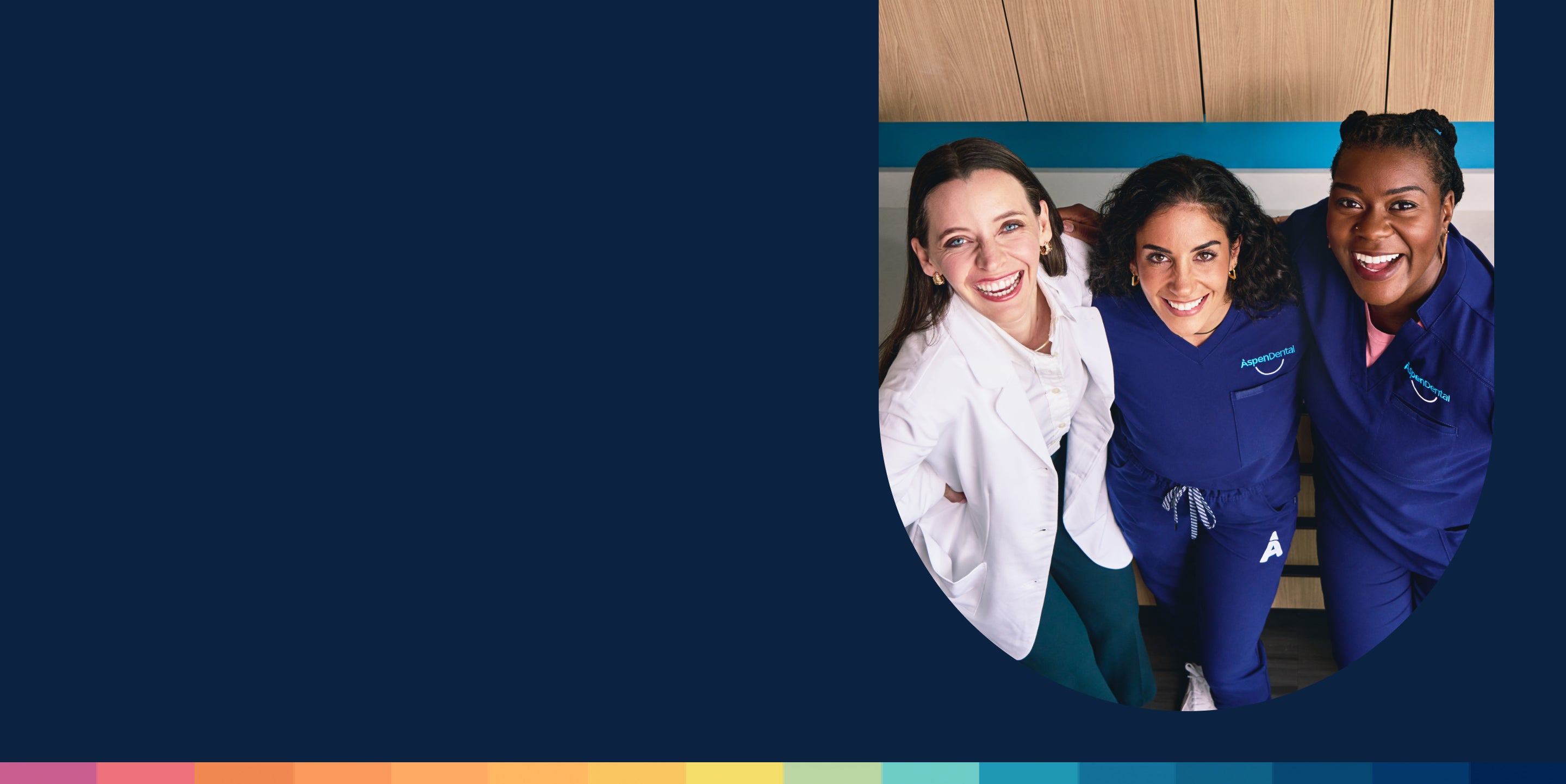 Three clear aligners experts, one in a white coat and two in blue scrubs, smile while standing together in a clinical setting.