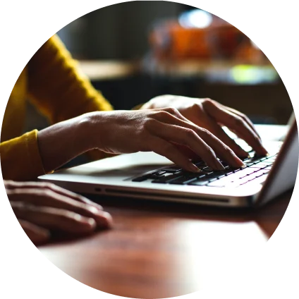 Hands type on a laptop keyboard.