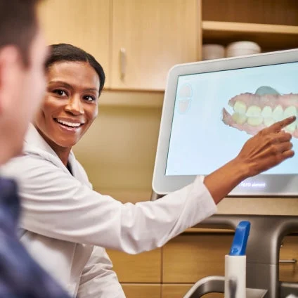A woman is pointing at a computer screen with a picture of teeth on it