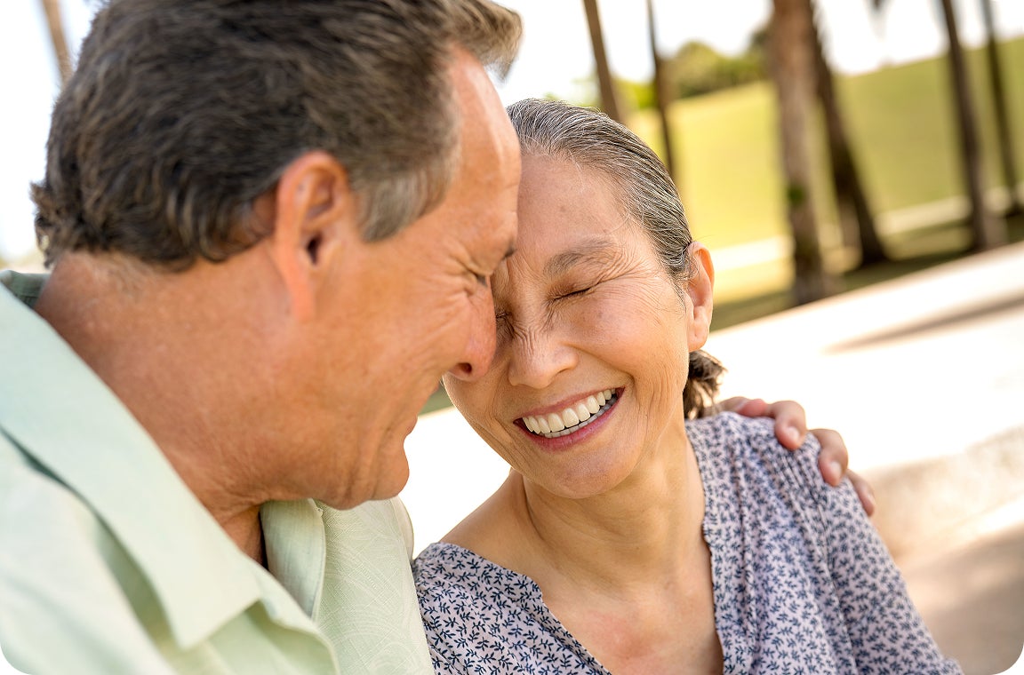 A smiling couple shares a quiet, joyful moment outdoors, showing the emotional benefits of supportive dental implant care and renewed confidence.