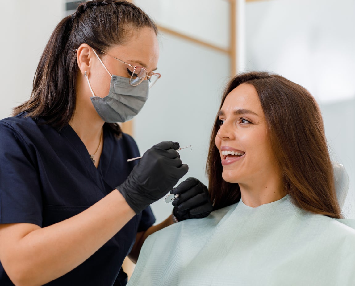 A dentist discusses treatment options with a woman during a dental visit, focusing on dental plaque concerns and oral hygiene guidance.