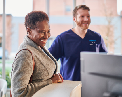 An Aspen Dental patient smiles while a doctor stands in the background