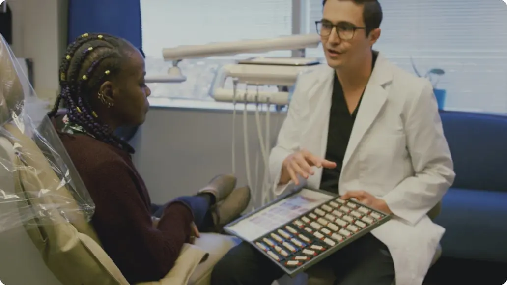 A ClearChoice dentist is talking to a patient who is sitting in a dentist chair.