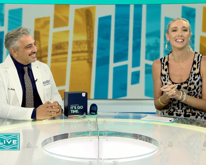 Dr. Ataii smiles at a news anchor while appearing during a television broadcast.