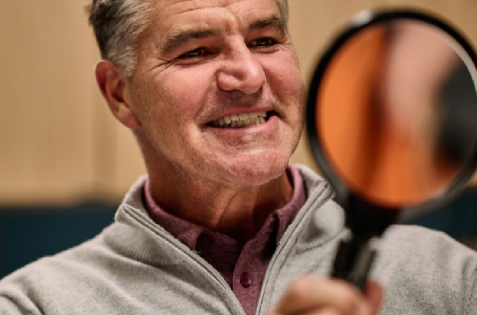 An Aspen Dental patient smiles into a handheld mirror. 