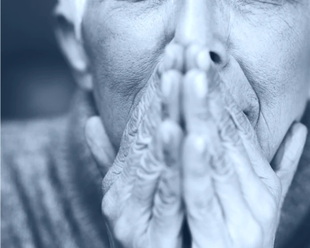 Black and white photo of closeup of a senior person's hands covering their mouth.