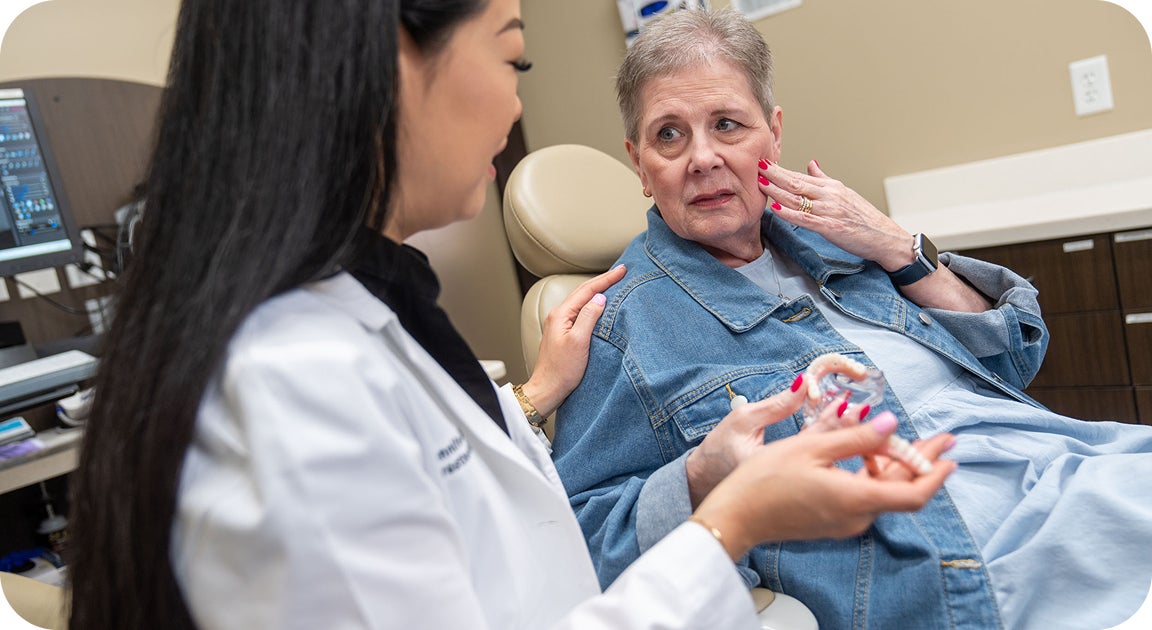 A ClearChoice provider discusses implant options with a senior patient, who expresses concern about jaw pain—demonstrating that even after years of denture use, personalized implant consultations remain possible and valuable.