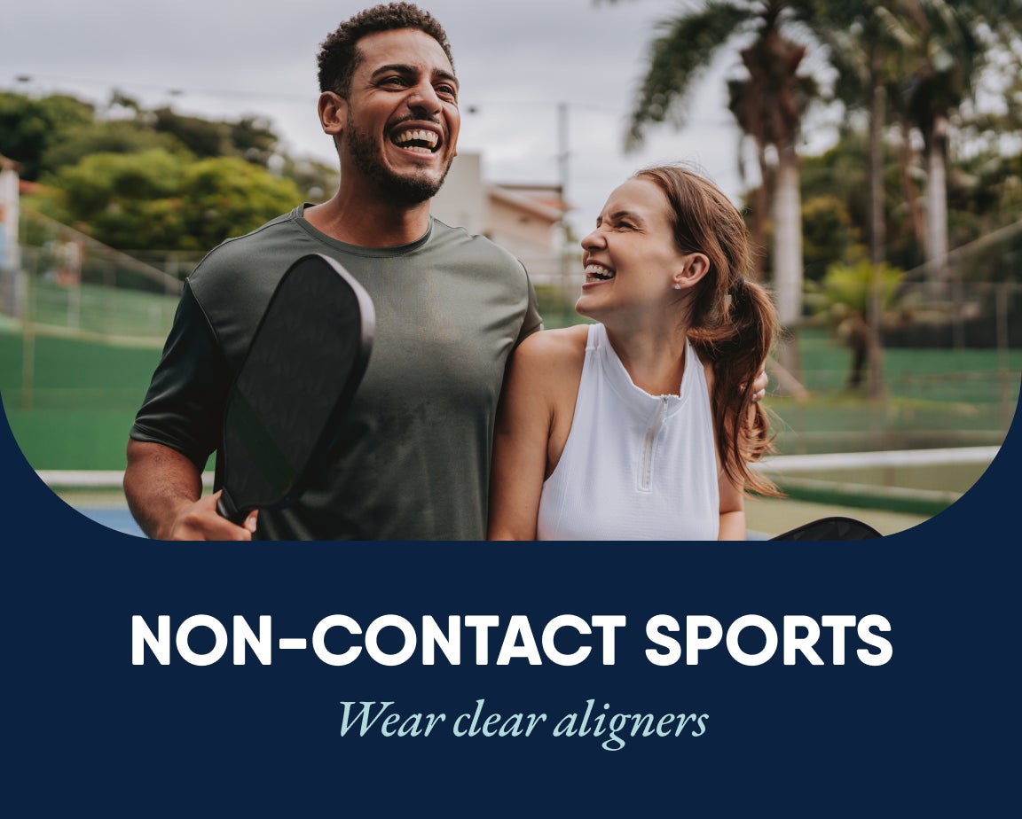 A smiling woman and a man hold tennis paddles or paddle racket on an outdoor court. The text reads, "Non-Contact Sports - Wear clear aligners.