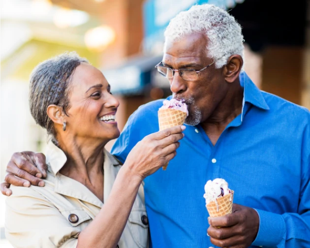 Happy senior couple sharing ice cream cones on a sunny day.