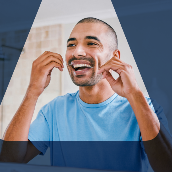 An Aspen Dental patient flosses his teeth in the mirror. 