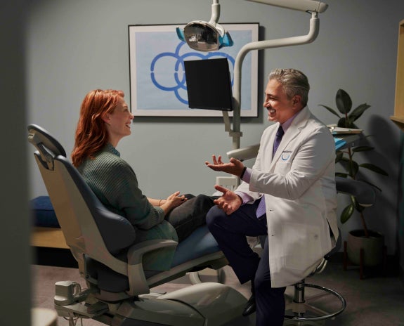 A patient sitting in a dental chair having a friendly conversation with a dentist during a post-holiday dental checkup, highlighting the importance of maintaining oral health after the holidays.