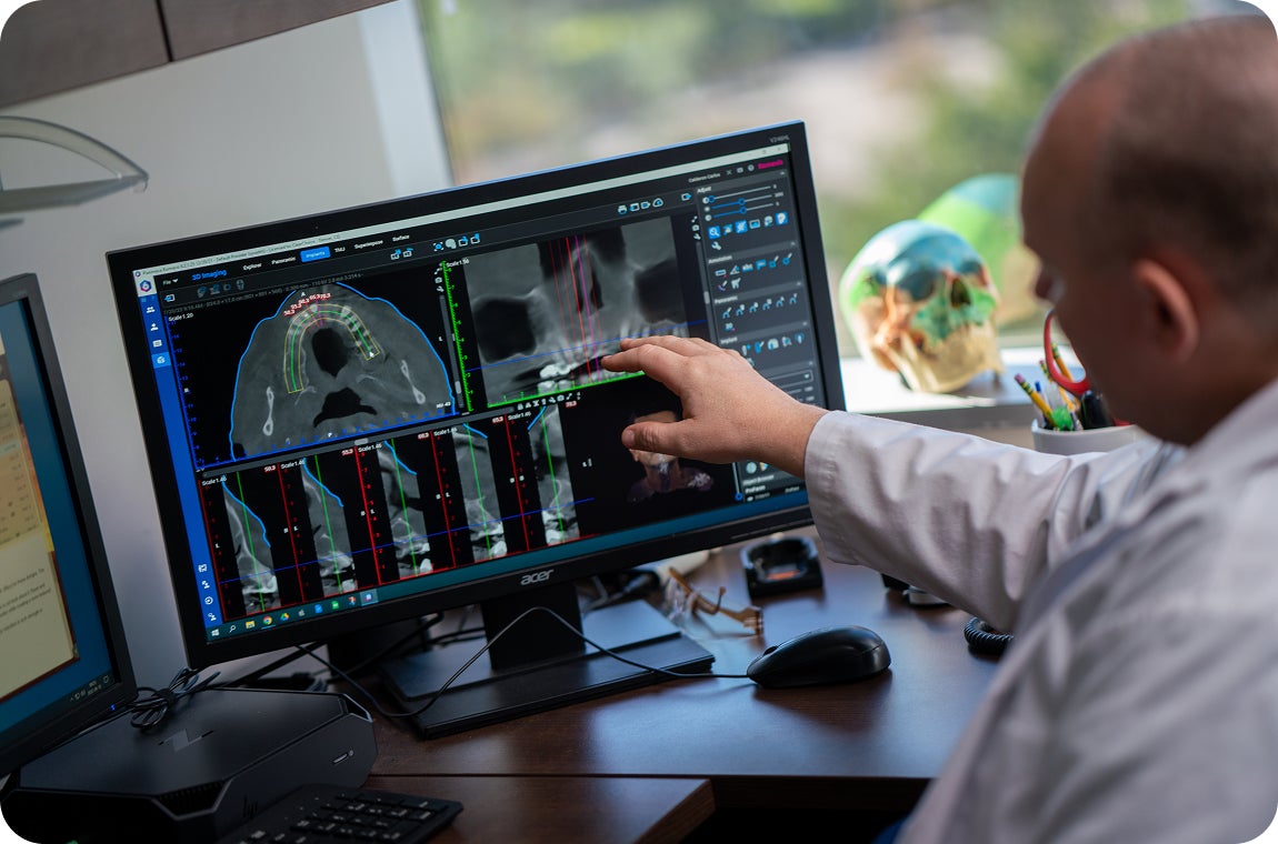 A ClearChoice prosthodontist showing a patient their scan results, and explaining to them why a delayed-load treatment plan would benefit them in creating long-lasting dental implants.