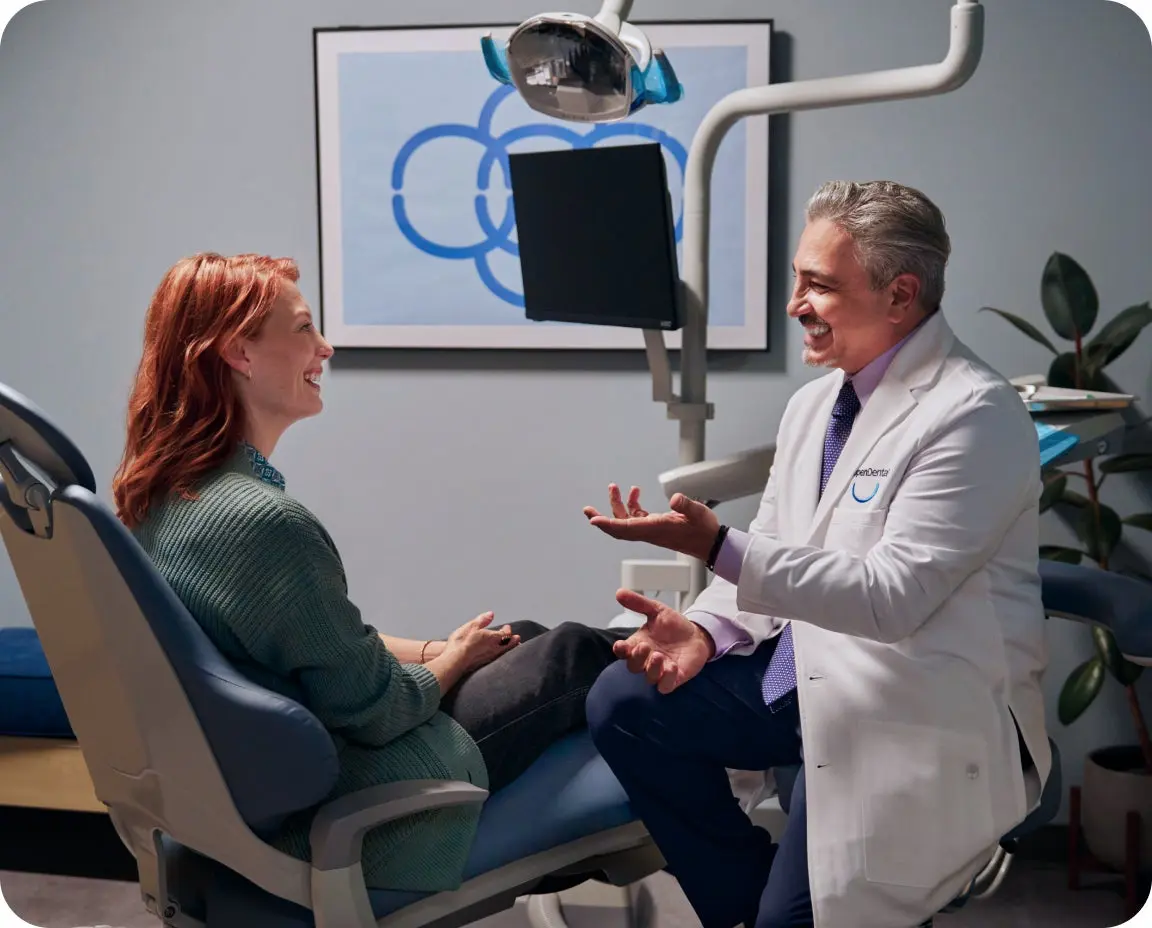 Dentist shows a dental X-ray to a patient during a root canal follow-up. Discussion focuses on safe eating habits and recovery progress.