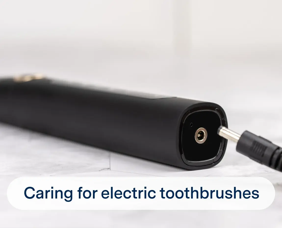 A close-up of an electric toothbrush being charged, with a charging cable inserted into the base. The text overlay reads, "Caring for electric toothbrushes.