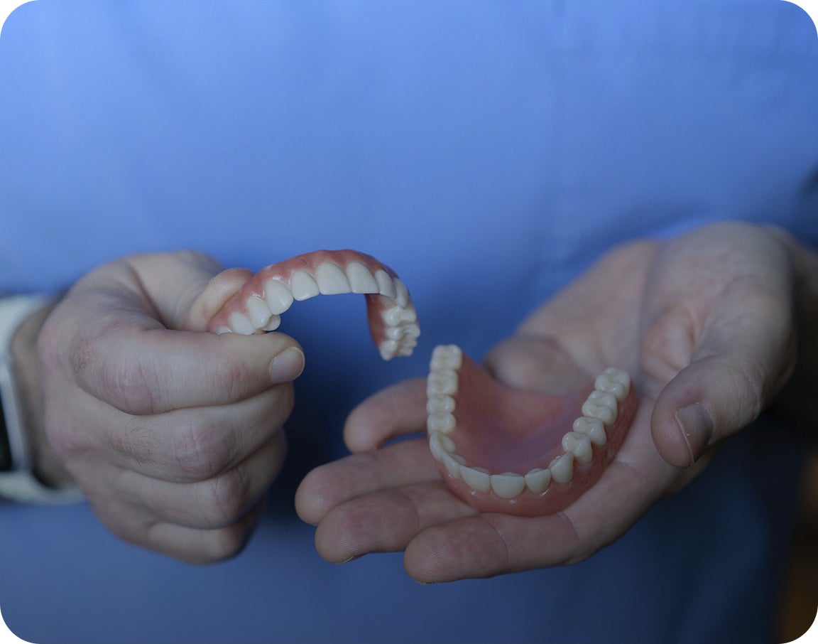 A ClearChoice professional holding an upper and a lower arch model, while walking their patients through the pros and cons of dental implants versus other teeth restoration solutions, such as dentures and bridges.