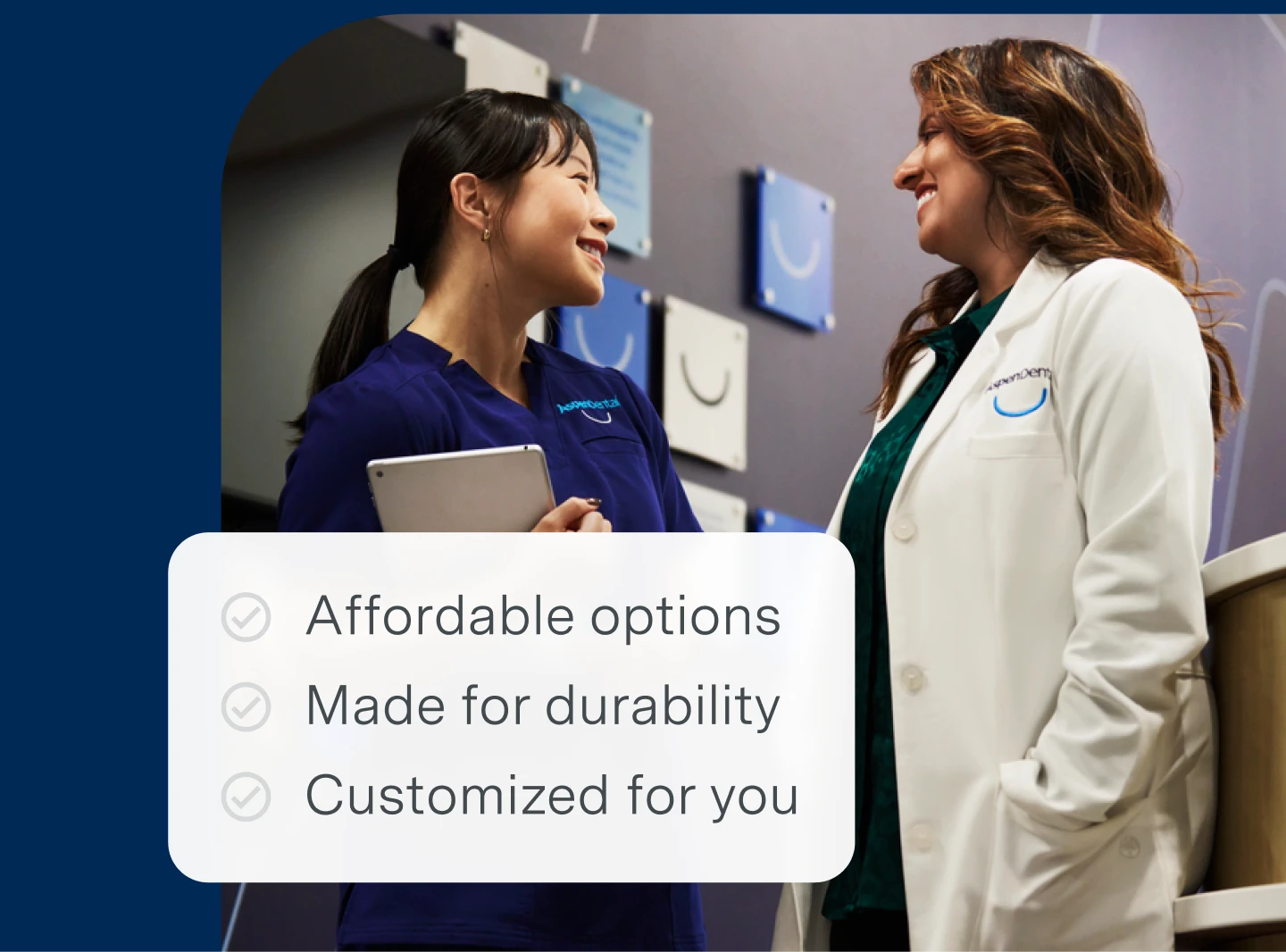 An Aspen Dental dentist and dental assistant engaged in conversation with the following bullet points on the image describing advantages of traditional full dentures:
Affordable options
Made for durability
Leading warranties