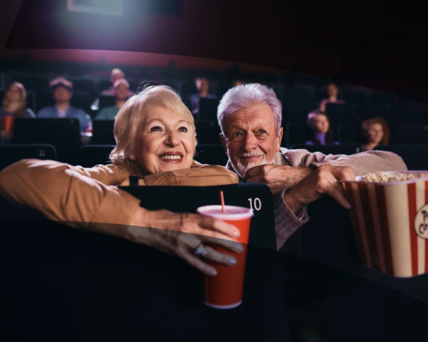 A couple enjoys a movie at the theater together. 