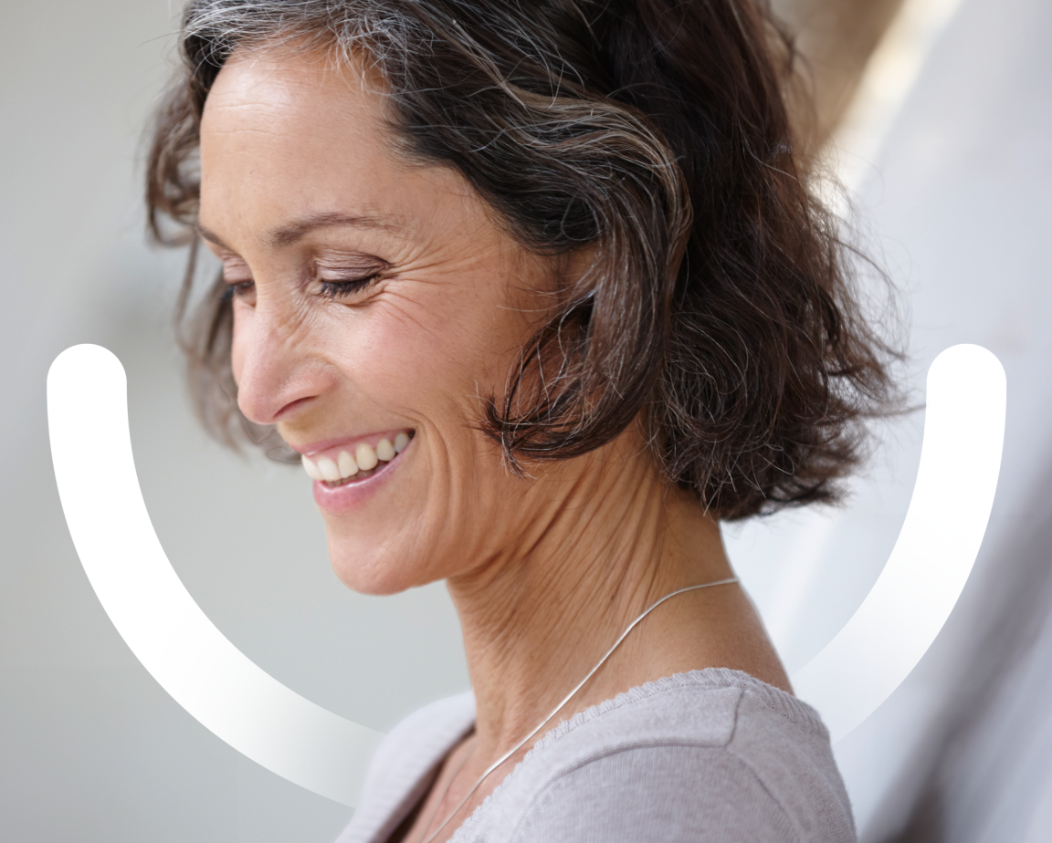 A side face of a woman smiling with the Aspen Dental smile icon on the background.