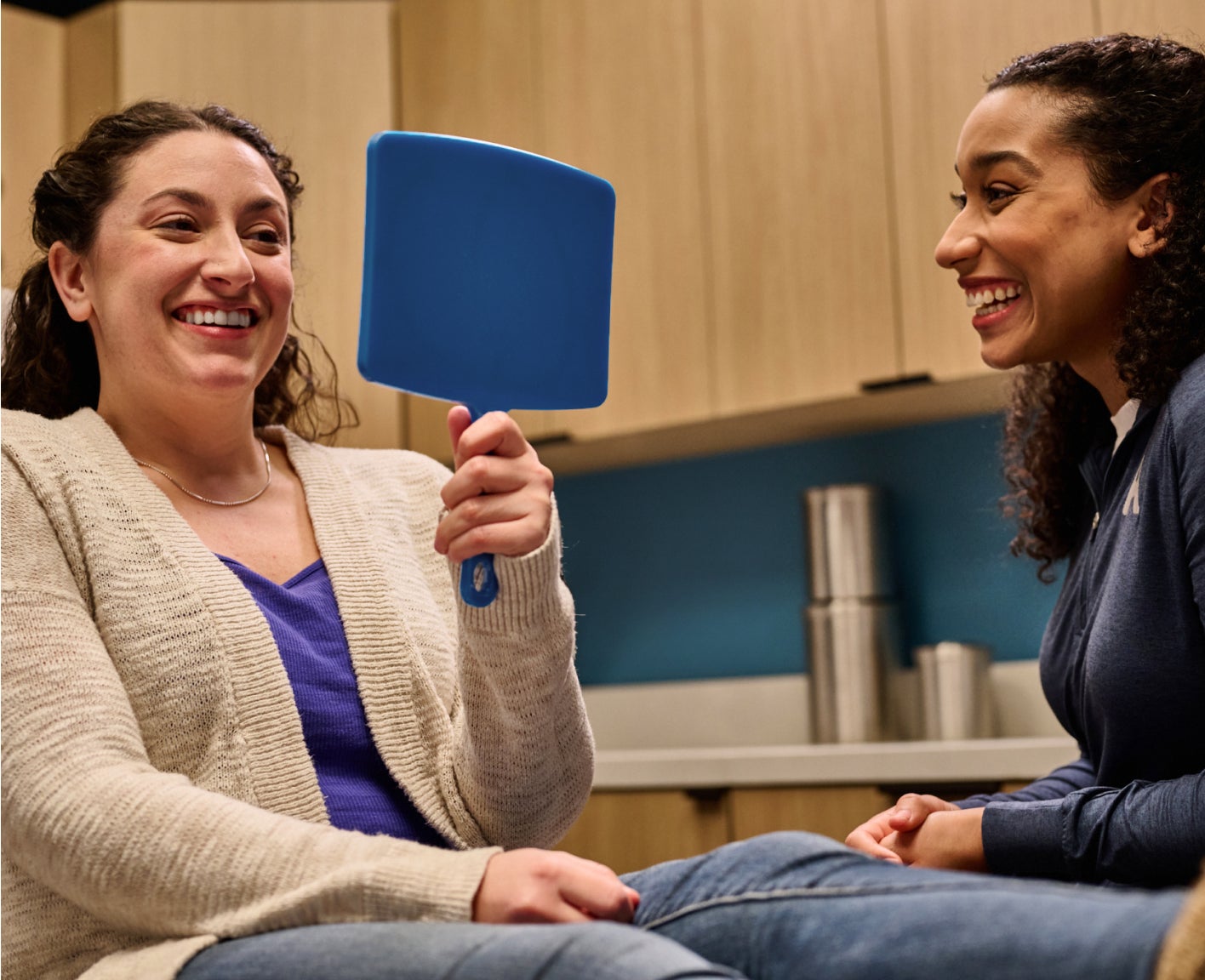 A Motto clear aligners patient smiles as they look into a handheld mirror
